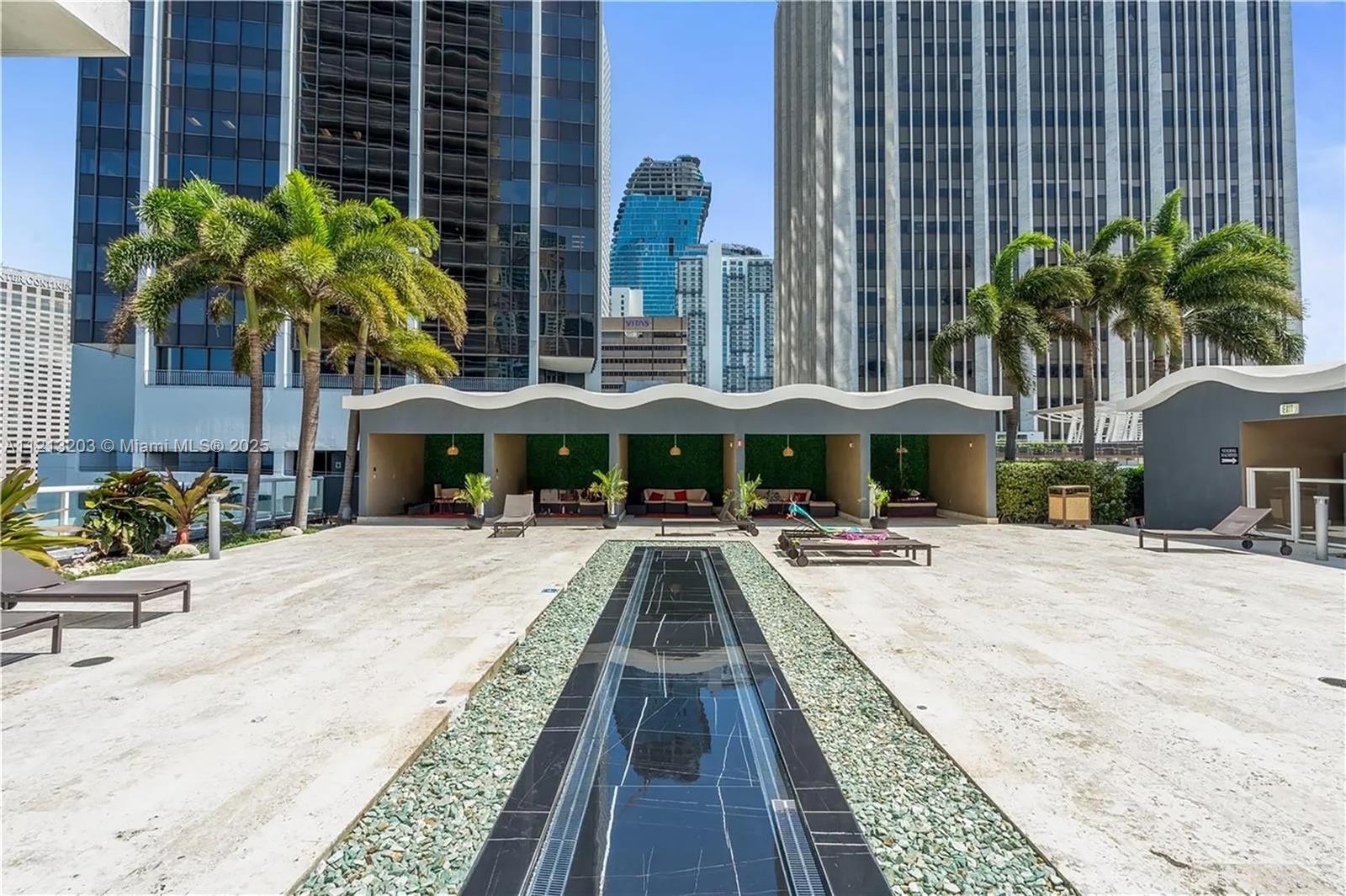 A rooftop terrace features a long, narrow reflecting pool, shaded cabanas, and lounge chairs — 50 Biscayne Blvd # 605, Miami FL 33132, MIAMI, FL