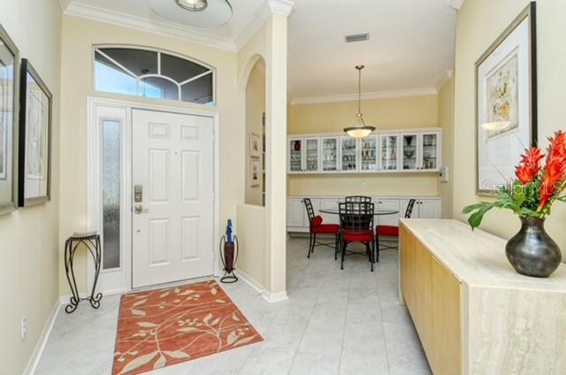 A bright entryway leads to a dining area with a built-in hutch and tile flooring — 9480 FOREST HILLS CIRCLE, SARASOTA, FL