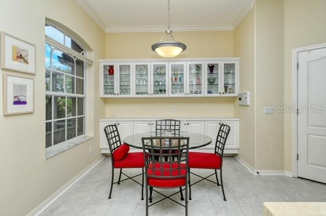 A dining area features a glass table, four red chairs, and white built-in cabinetry — 9480 FOREST HILLS CIRCLE, SARASOTA, FL