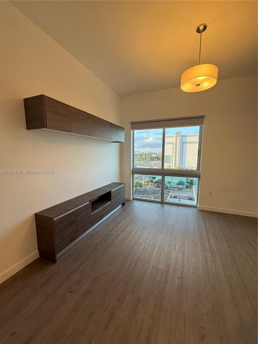 A room with wood-look flooring, wall-mounted cabinetry, and a window overlooking a parking lot — 61 NW 37th Ave # 22, Miami FL 33125, MIAMI, FL