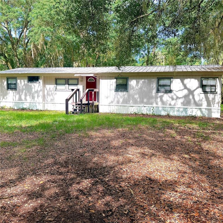A single-story mobile home with a metal roof and a red front door — 7526 NE 221ST STREET, MELROSE, FL