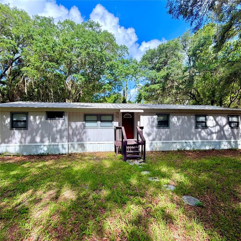 A single-story manufactured home with light-colored siding and a small wooden front porch — 7526 NE 221ST STREET, MELROSE, FL