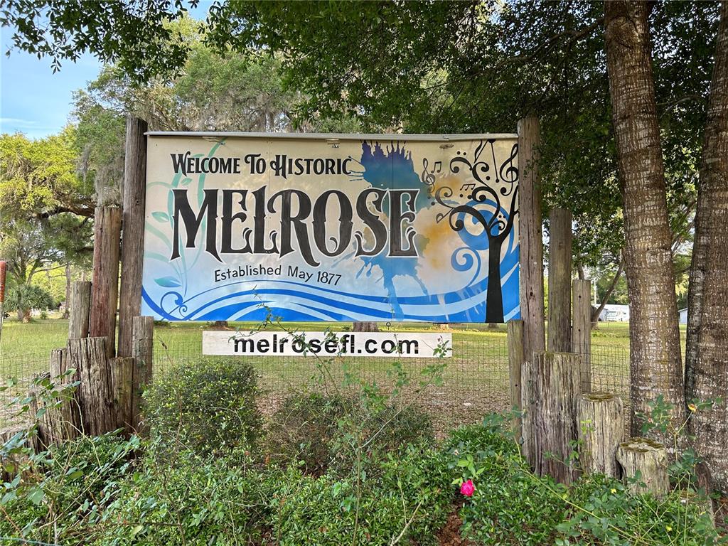 A wooden sign welcomes visitors to historic Melrose, Florida, mounted between two large trees — 7526 NE 221ST STREET, MELROSE, FL