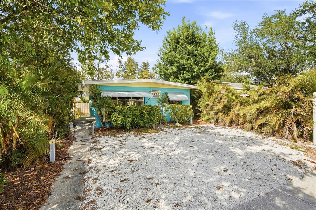 A turquoise single-story house with a gravel driveway and lush tropical landscaping — 4933 13TH AVENUE S, GULFPORT, FL