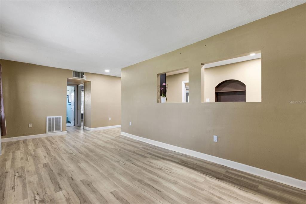 An empty room with light wood-look flooring and two cutouts in the tan wall — 3341 CROTON TERRACE, PORT CHARLOTTE, FL