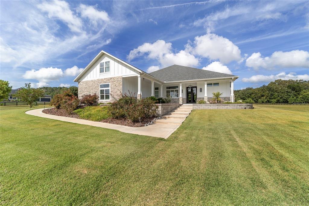 A single-story house with white siding, stone accents, and a front walkway on a lawn — 10630 NW 153RD TERRACE, ALACHUA, FL