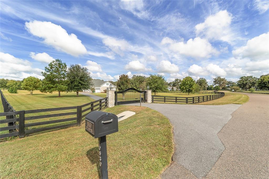 A paved driveway leads to a gated entrance with black fencing and a mailbox — 10630 NW 153RD TERRACE, ALACHUA, FL