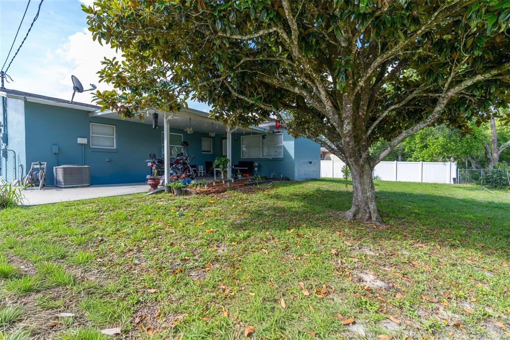A blue house exterior features a covered patio, a large tree, and a grassy yard — 306 S MONROE STREET, BEVERLY HILLS, FL