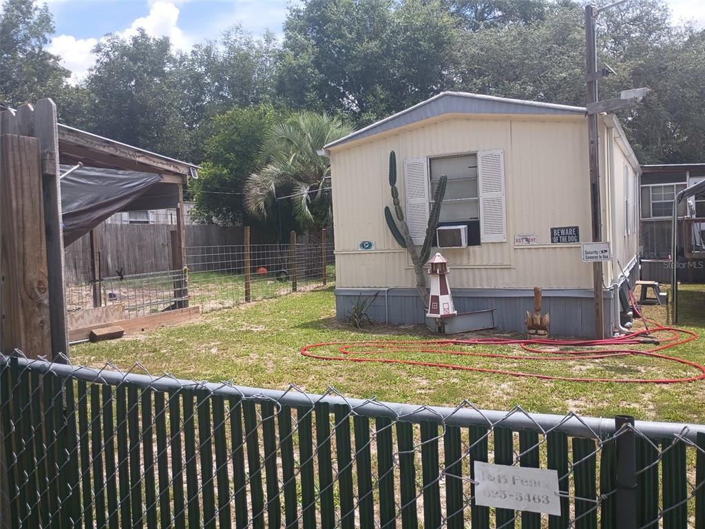 A mobile home with a fenced yard, a small lighthouse statue, and a cactus — 711 SE 129TH COURT, SILVER SPRINGS, FL