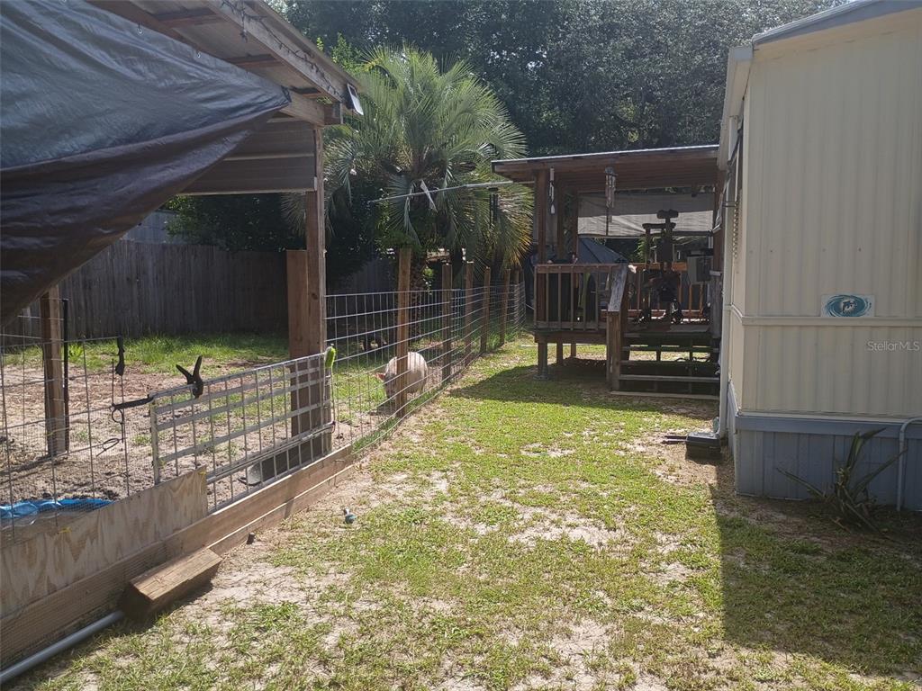 A fenced yard features a pig, a covered patio, and a mobile home exterior — 711 SE 129TH COURT, SILVER SPRINGS, FL