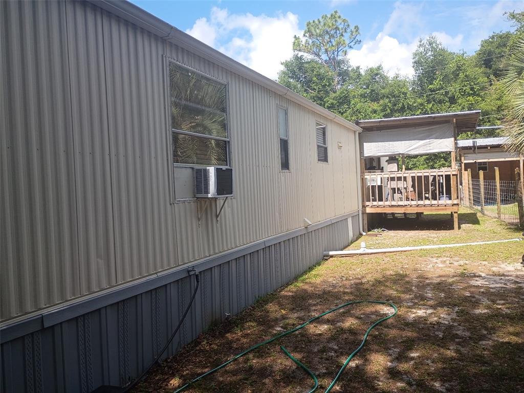 The exterior side of a mobile home features metal siding, a window air conditioner, and skirting — 711 SE 129TH COURT, SILVER SPRINGS, FL