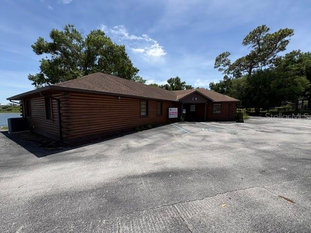 A brown log-style commercial building sits next to a parking lot under a blue sky — 29 SR-60, LAKE WALES, FL