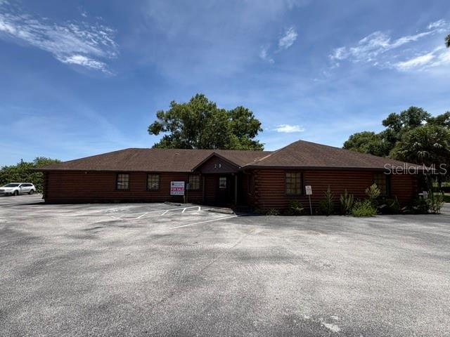 A single-story log cabin style commercial building features a large asphalt parking lot — 29 SR-60, LAKE WALES, FL