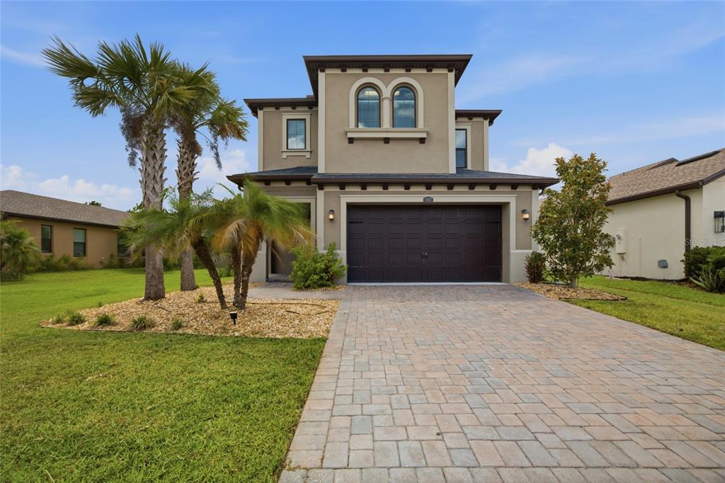 A two-story house with a brown garage door, arched windows, and a paved driveway — 4667 SAN MARTINO DRIVE, WESLEY CHAPEL, FL