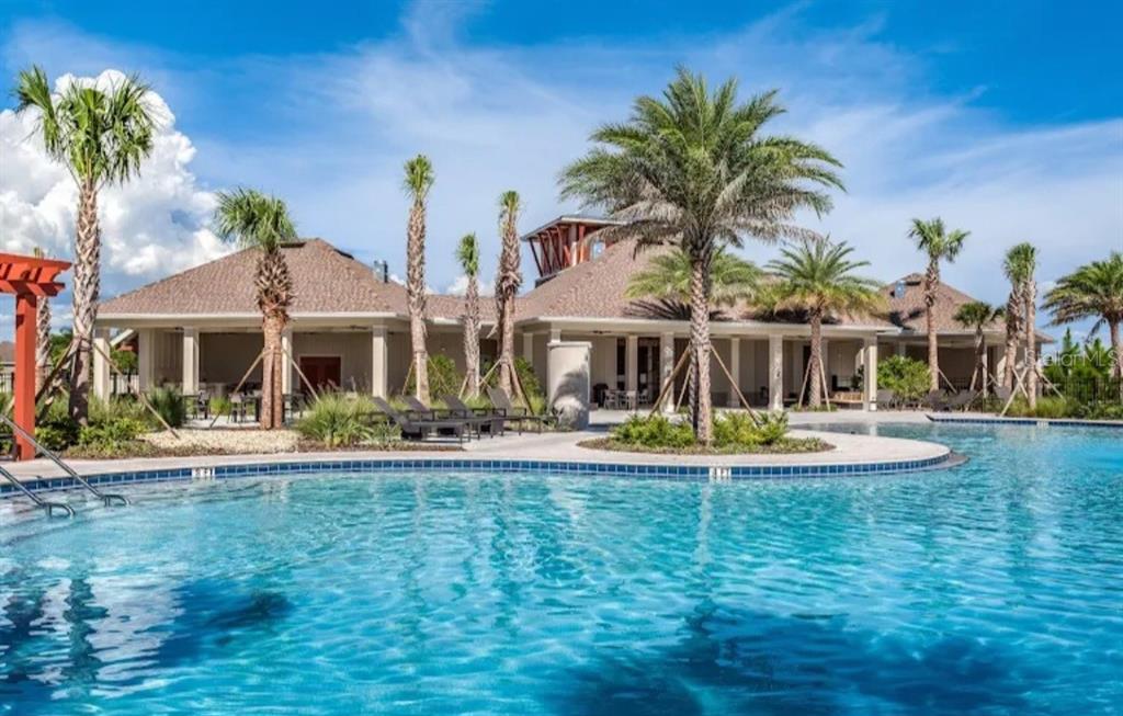 A swimming pool sits in front of a clubhouse building surrounded by several palm trees — 6531 TRENT CREEK DRIVE, RUSKIN, FL