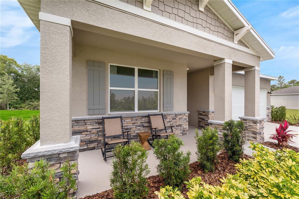 A covered front porch features stone accents, two rocking chairs, and a small side table — 1713 FLAG STREET, HAINES CITY, FL