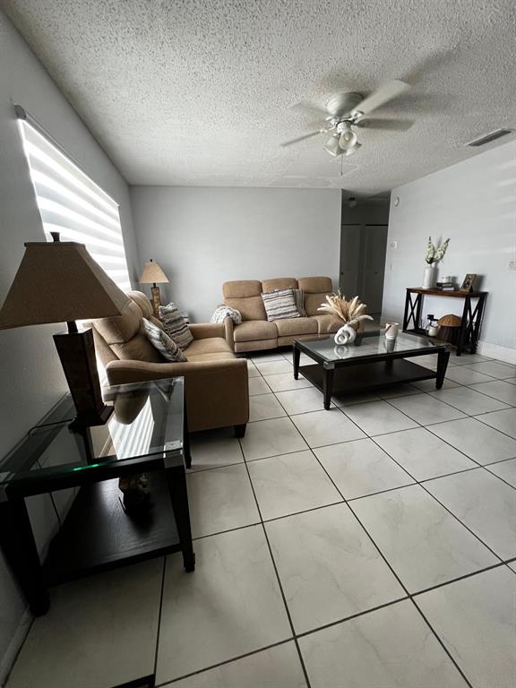 A living room features light-colored tile flooring, a tan sofa, and a glass-topped coffee table — 26 LAS PALMAS WAY UNIT 1, KISSIMMEE, FL