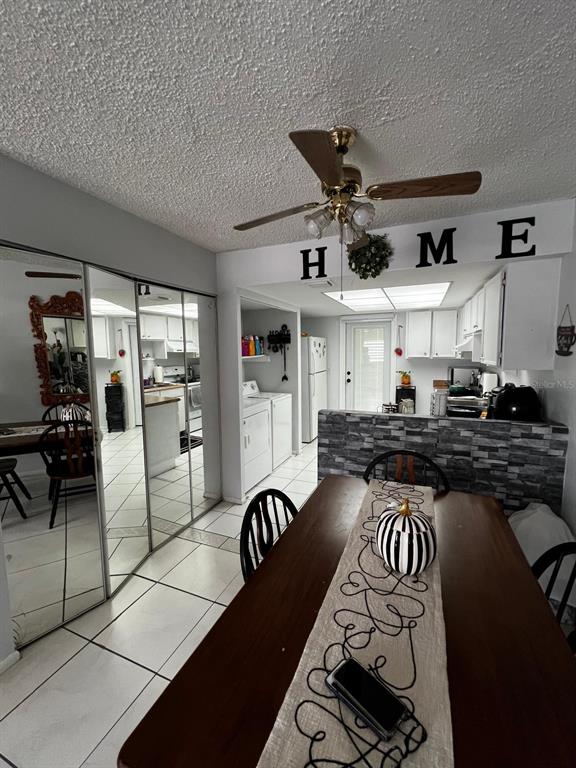 A dining area with a wooden table and mirrored closet doors overlooks a kitchen — 26 LAS PALMAS WAY UNIT 1, KISSIMMEE, FL