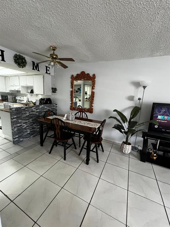 A dining area with a wooden table, chairs, a decorative mirror, and a tiled floor — 26 LAS PALMAS WAY UNIT 1, KISSIMMEE, FL