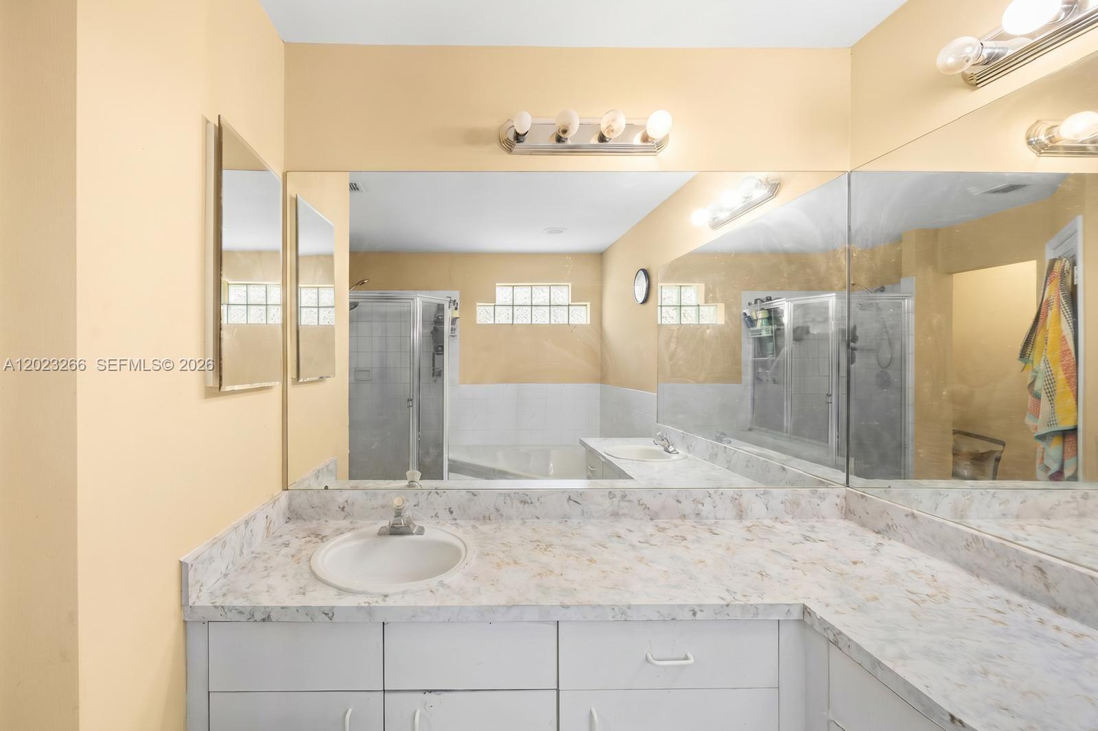 A bathroom features a white vanity with a marble-look countertop and a large wall mirror — 12360 SW 145th St, Miami FL 33186, MIAMI, FL