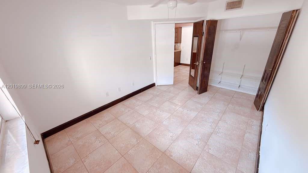 A bedroom with tile flooring, a closet with open doors, and a doorway to another room — 470 S Park Rd # 104, Hollywood FL 33021, HOLLYWOOD, FL