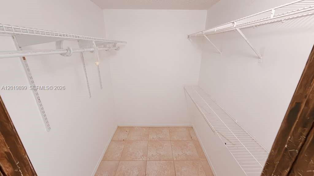 A walk-in closet features white walls, tiled flooring, and white wire shelving units — 470 S Park Rd # 104, Hollywood FL 33021, HOLLYWOOD, FL