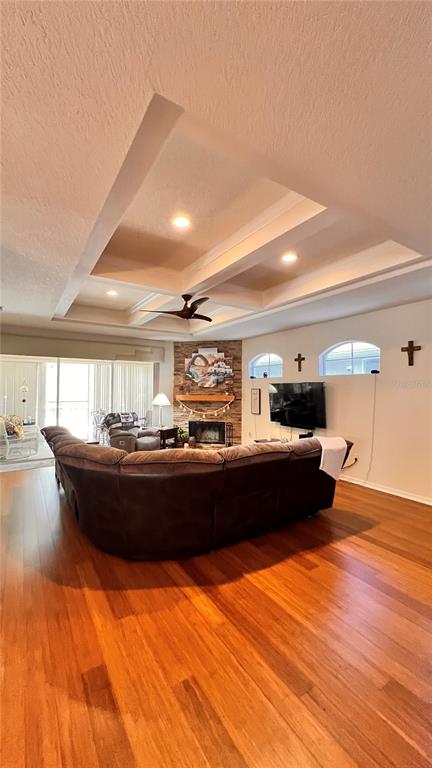 A living room features a coffered ceiling, hardwood floors, a stone fireplace, and a sectional sofa — 5561 LEGEND HILLS LANE, SPRING HILL, FL