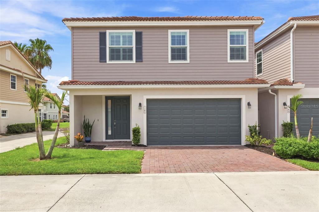 A two-story house with a gray garage, beige siding, and a brick paver driveway — 1805 NOEL PLACE UNIT 101, MELBOURNE, FL
