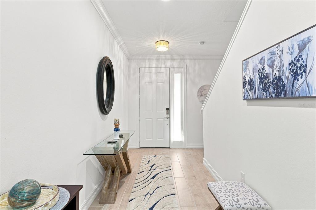 A bright entryway features white walls, a glass console table, and a patterned runner rug — 1805 NOEL PLACE UNIT 101, MELBOURNE, FL