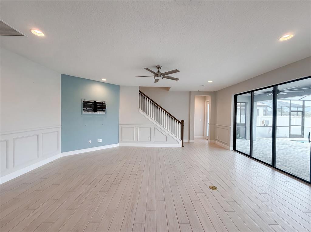 A living room features light wood-look flooring, a blue accent wall, and a staircase — 13176 TWIN BRIDGES DRIVE, RIVERVIEW, FL