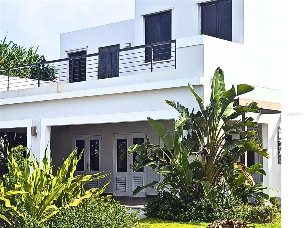 A two-story white modern house features a balcony with a metal railing and lush landscaping — 24.25 HARBORVIEW ROAD, HUMACAO, PR