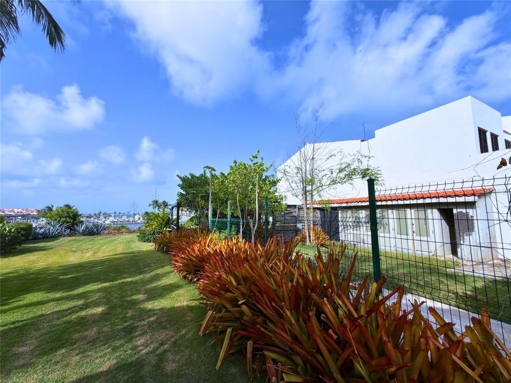 A two-story white villa features a tiled patio, outdoor seating, and a balcony — 24.25 HARBORVIEW ROAD, HUMACAO, PR