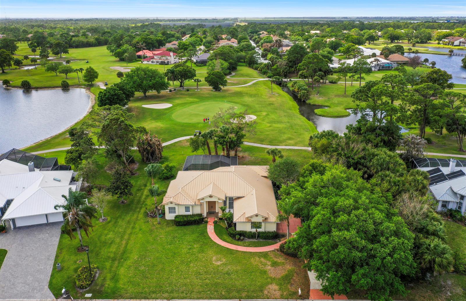 An aerial view of a single-story house with a metal roof overlooking a golf course — 2987 Conifer Drive, Fort Pierce FL 34951, FORT PIERCE, FL