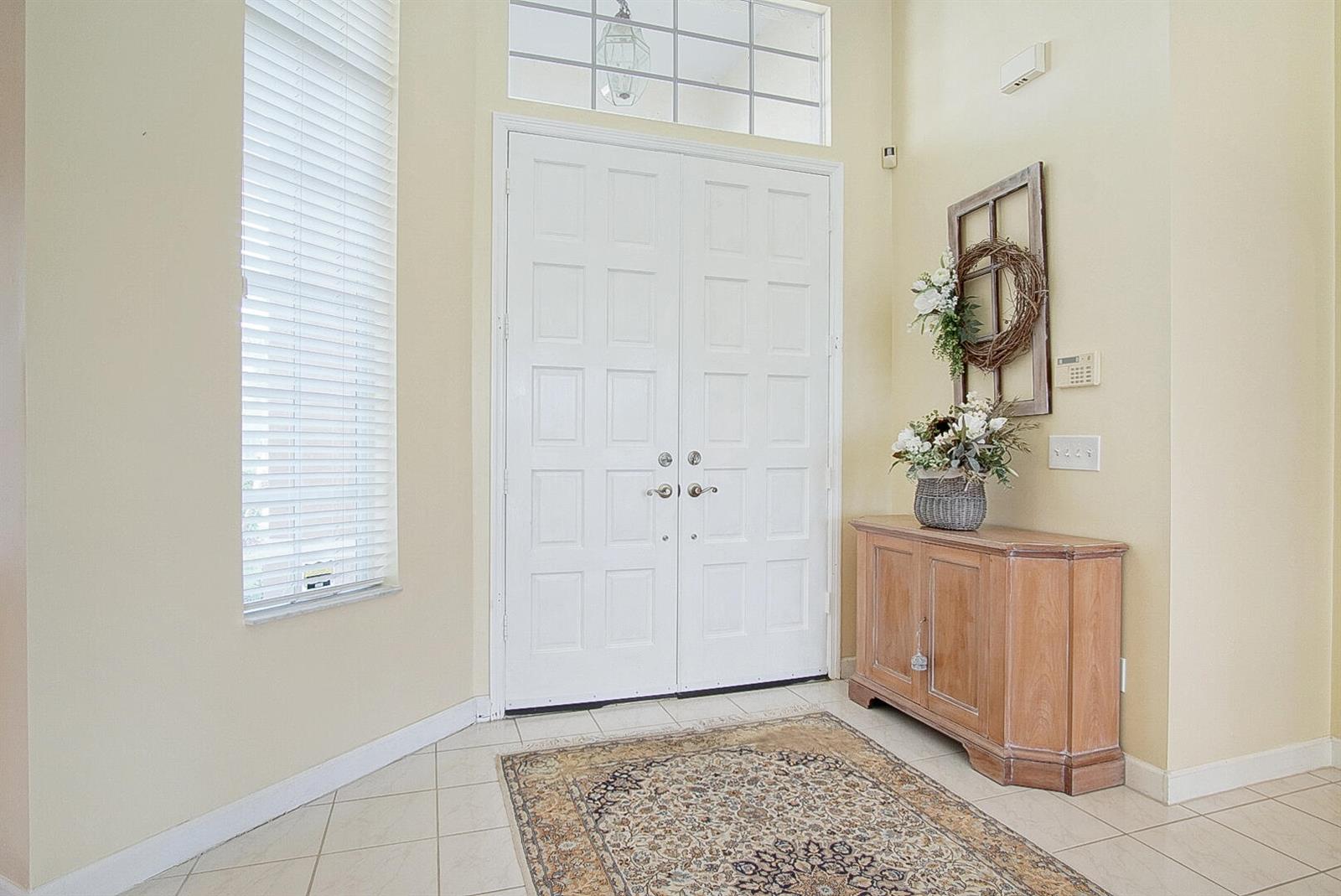 A foyer features tile flooring, a wooden cabinet, a double door, and a decorative rug — 2987 Conifer Drive, Fort Pierce FL 34951, FORT PIERCE, FL