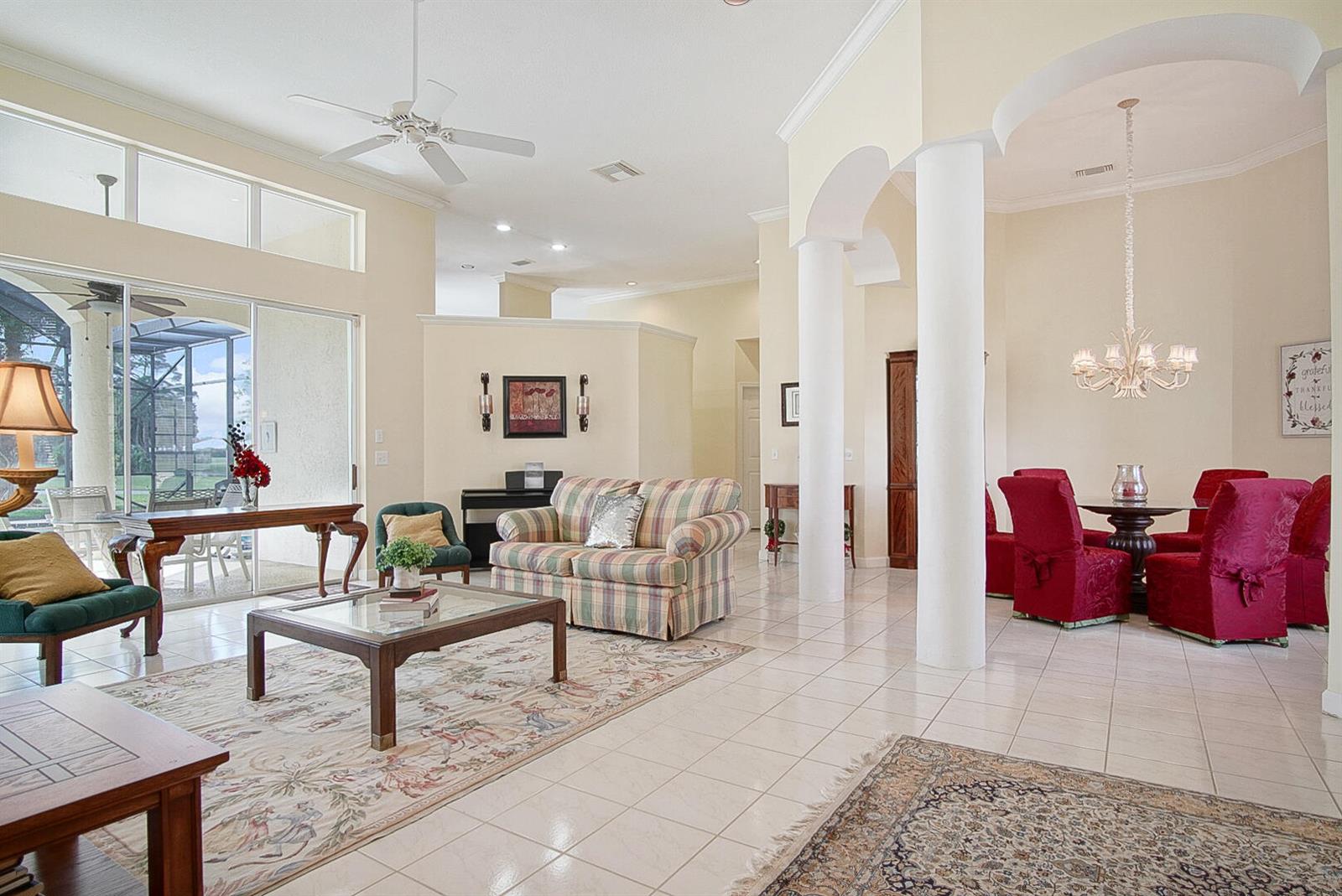 A living and dining area with tile floors, white columns, and large sliding glass doors — 2987 Conifer Drive, Fort Pierce FL 34951, FORT PIERCE, FL