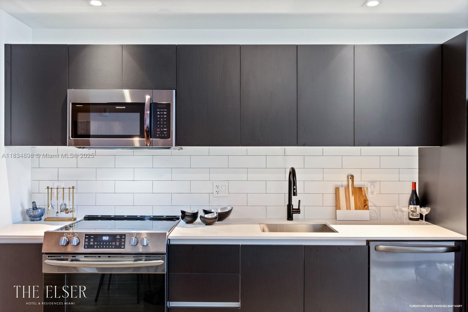 A modern kitchen features dark wood cabinetry, white subway tile backsplash, and stainless steel appliances — 398 NE 5th St # 4018, Miami FL 33132, MIAMI, FL