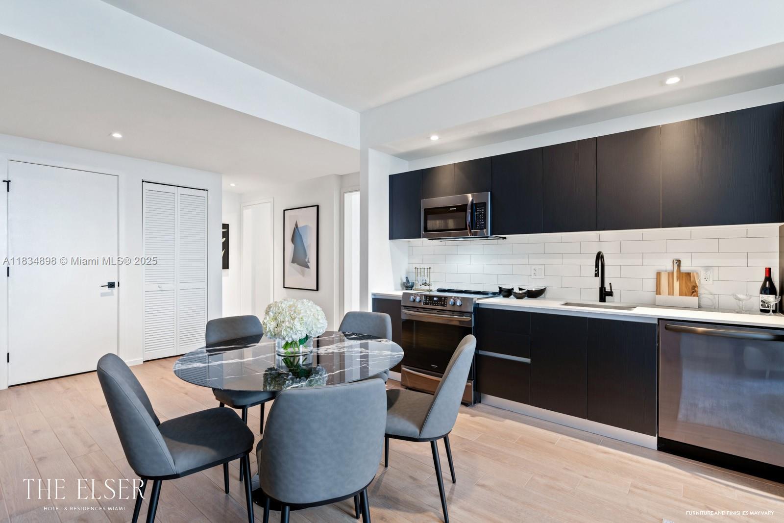 A modern kitchen features dark cabinetry, a marble-topped dining table, and light wood flooring — 398 NE 5th St # 4018, Miami FL 33132, MIAMI, FL