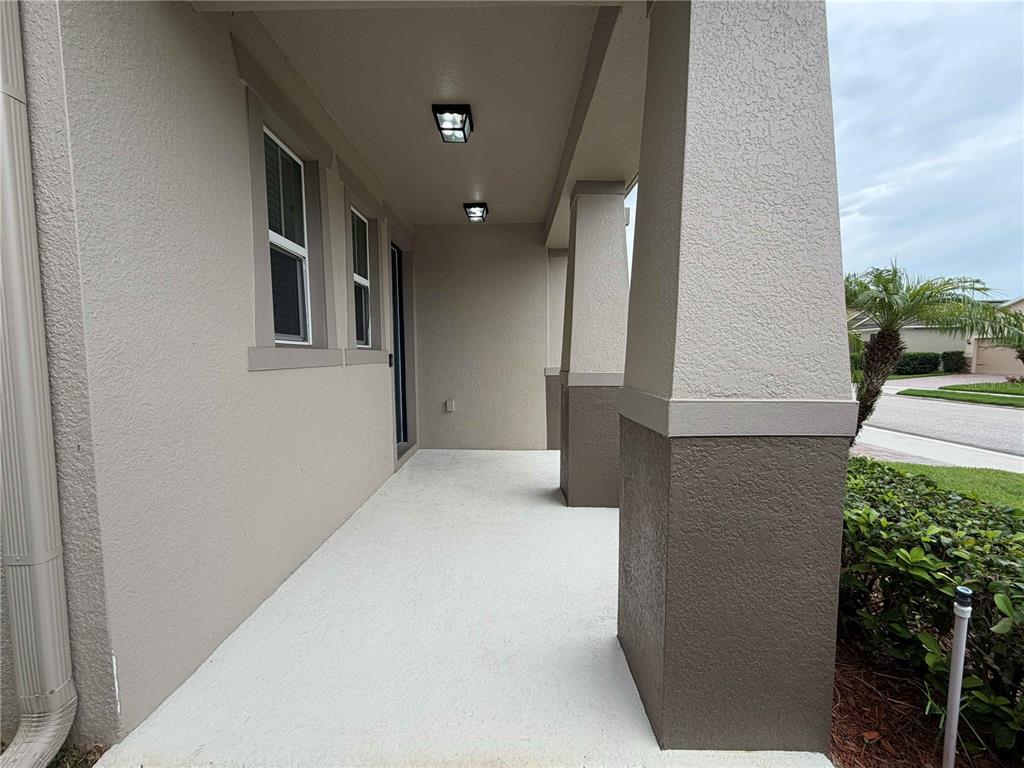 A covered concrete porch features two square support columns and two ceiling-mounted light fixtures — 476 BOTTLEBRUSH LOOP, SANFORD, FL