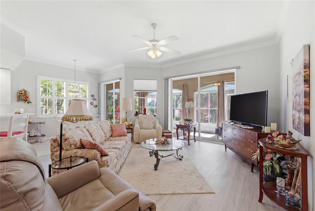 A living room features a floral sofa, a glass coffee table, and sliding glass doors — 4000 IBIS WAY UNIT 101, VENICE, FL