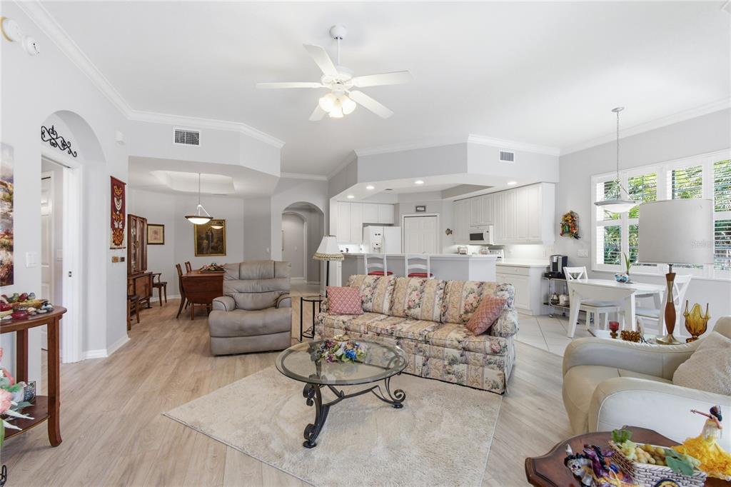 An open-concept living room features a floral sofa, glass coffee table, and adjacent kitchen area — 4000 IBIS WAY UNIT 101, VENICE, FL
