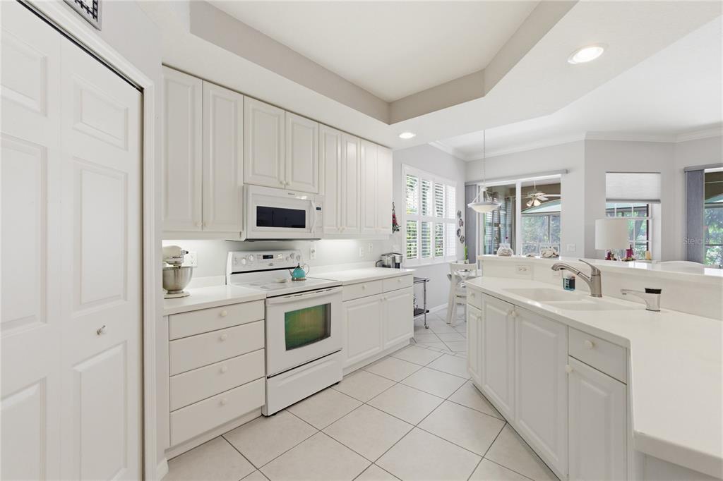 A bright kitchen features white cabinets, white countertops, white appliances, and light-colored tile flooring — 4000 IBIS WAY UNIT 101, VENICE, FL