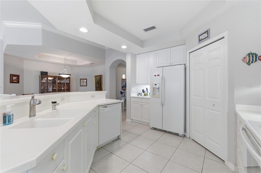 A white kitchen features tile flooring, white cabinetry, a double sink, and a side-by-side refrigerator — 4000 IBIS WAY UNIT 101, VENICE, FL