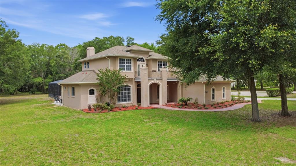 A two-story stucco house with a shingled roof sits on a large, grassy lot — 530 N BLUE LAKE AVENUE, DELAND, FL