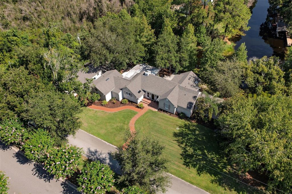 An aerial view shows a single-story house with a gray roof surrounded by lush trees — 12085 SANDY SHORES DRIVE UNIT D, WINDERMERE, FL