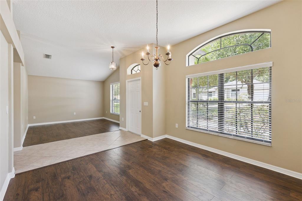 An empty dining room with dark wood floors, a chandelier, and a large arched window — 1106 NATURAL OAKS DRIVE, ORANGE CITY, FL