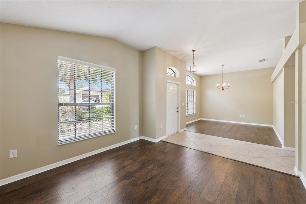 An interior view of a room with dark wood flooring, beige walls, and a tiled entryway — 1106 NATURAL OAKS DRIVE, ORANGE CITY, FL
