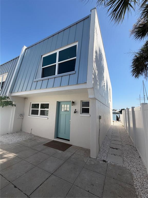 A two-story house with blue metal siding, a teal front door, and a stone patio — 716 BAYWAY BOULEVARD UNIT 6, CLEARWATER BEACH, FL