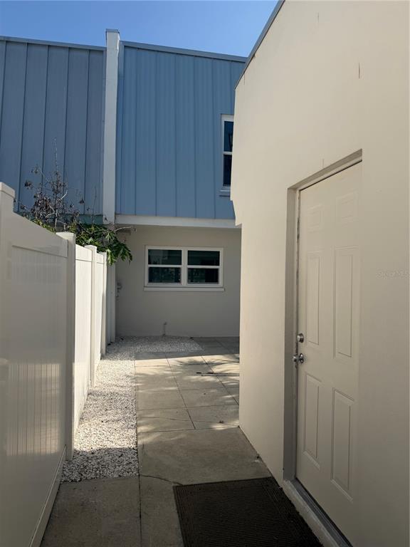 A narrow paved walkway leads to a white door beside a white vinyl fence — 716 BAYWAY BOULEVARD UNIT 6, CLEARWATER BEACH, FL