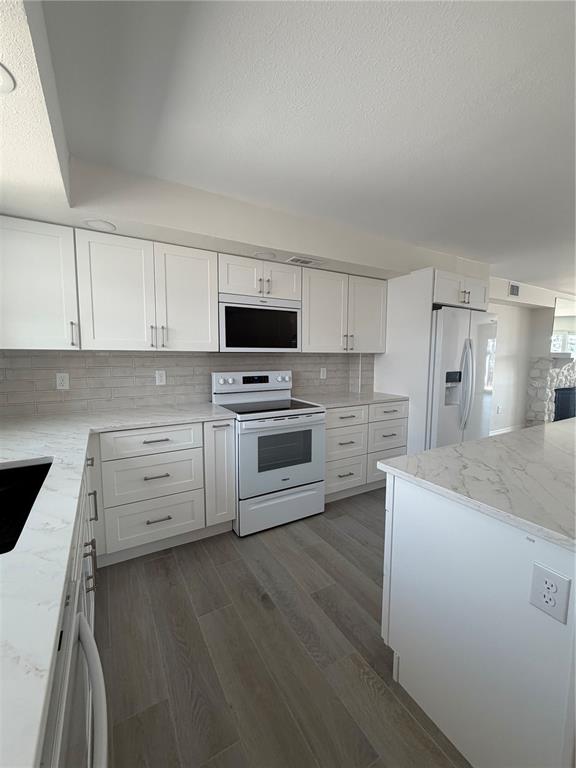 A kitchen features white cabinets, stainless steel appliances, and a marble-patterned island countertop — 716 BAYWAY BOULEVARD UNIT 6, CLEARWATER BEACH, FL