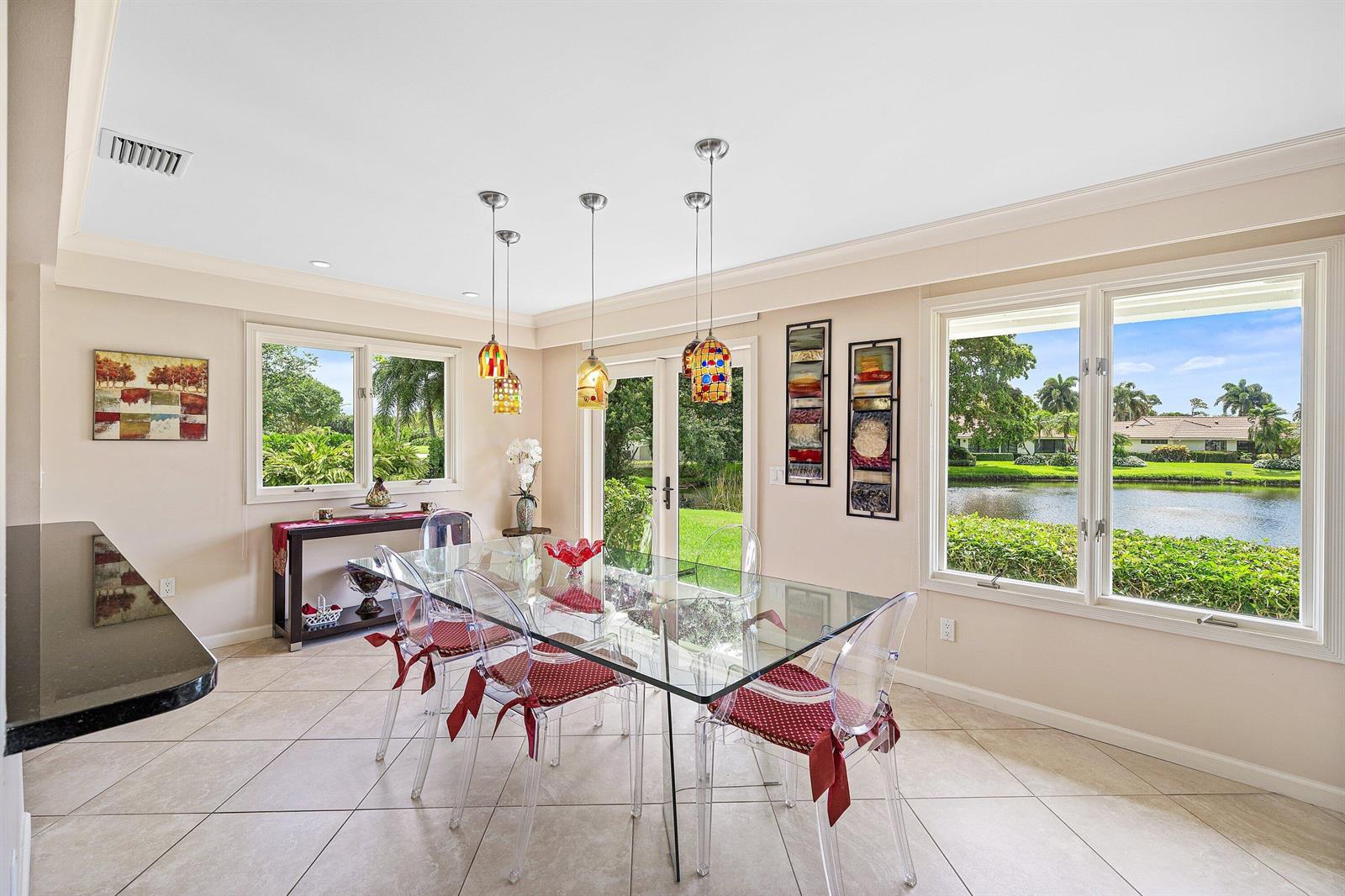 A dining room features a glass table, clear chairs, pendant lights, and a waterfront view — 4365 Shelldrake Lane, Boynton Beach FL 33436, BOYNTON BEACH, FL